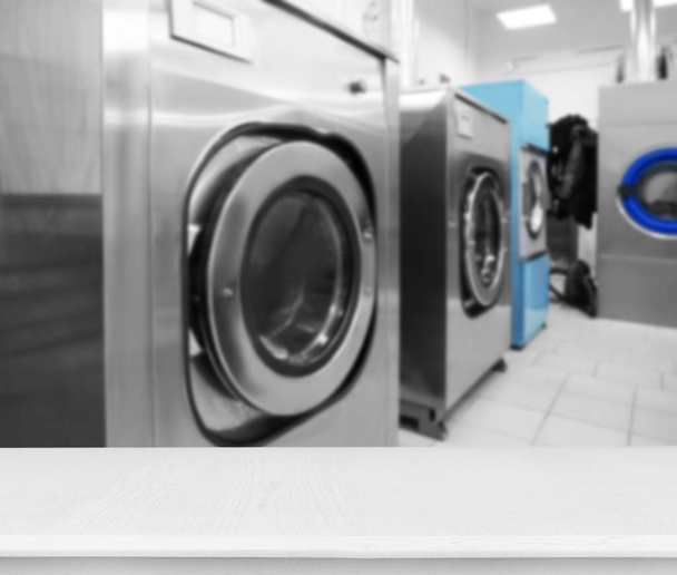Стіл і пральні машини на пральні самообслуговування
 - Фото, зображення