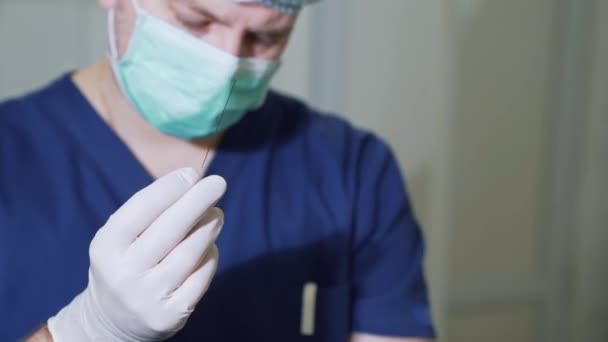 Close up surgeon demonstrates a large metal needle. The doctor examines medical equipment in sterile gloves. Needle for shunting of varicose veins. - Materiał filmowy, wideo
