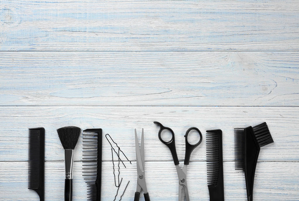 Flat lay composition with professional hairdresser's tools on wooden background - Photo, image