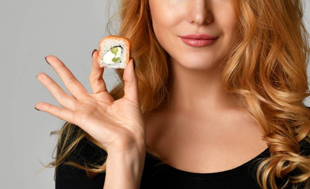 Woman with sushi girl hold sushi rolls in hands smiling on a light gray  - Photo, Image