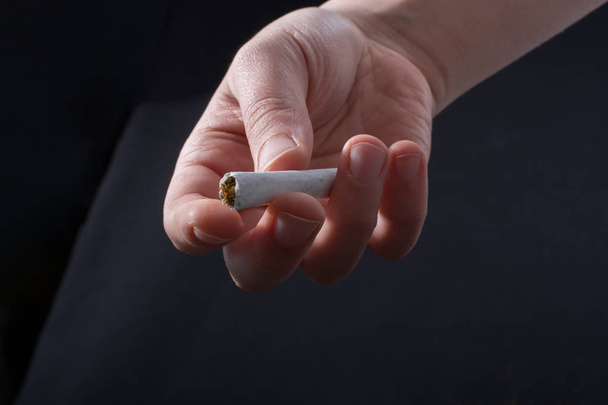 Hand is het uitdelen van sigaretten op een zwarte achtergrond - Foto, afbeelding