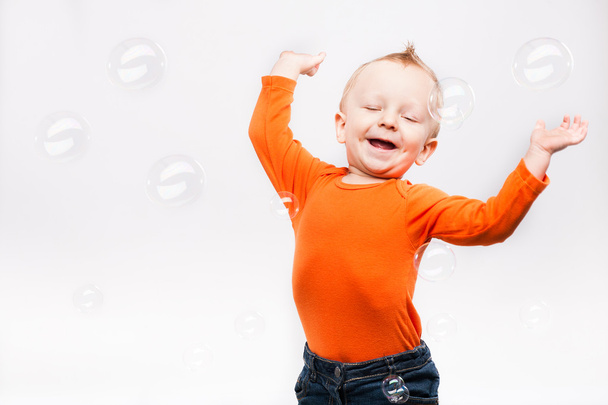 Photo of little boy onlight grey background, playing with soap b - Foto, Bild