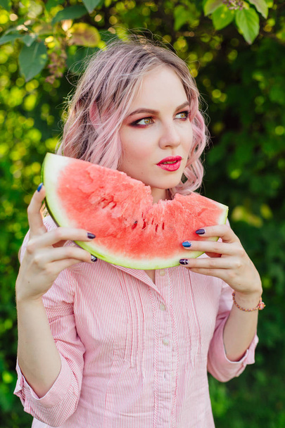 Beautiful young woman with pink hair enjoying watermelon - Foto, Imagen