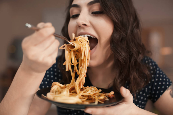 Young woman eating tasty pasta in cafe - Photo, Image