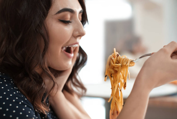 Young woman eating tasty pasta in cafe - Foto, Imagen