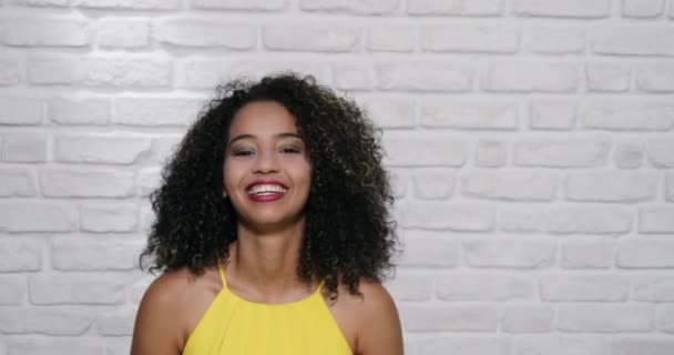 Mimika młody czarny kobieta na ceglany mur - Materiał filmowy, wideo