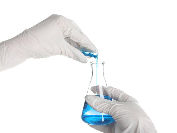 Woman pouring blue liquid from test tube into flask on white background - Foto, Imagen