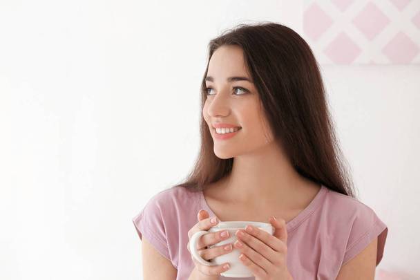 Beautiful young woman with cup of hot tea at home - Fotó, kép
