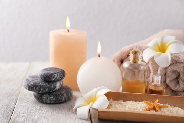 Wellness-Komposition mit Meersalz, Kerzen und Handtüchern auf hellem Hintergrund - Foto, Bild
