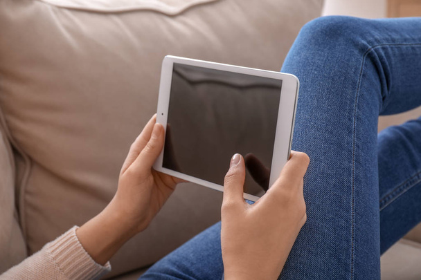 Fiatal nő segítségével tabletta számítógép, miközben otthon a kanapén pihen - Fotó, kép