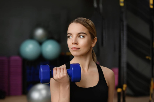 Young woman training with dumbbell in modern gym - Фото, изображение