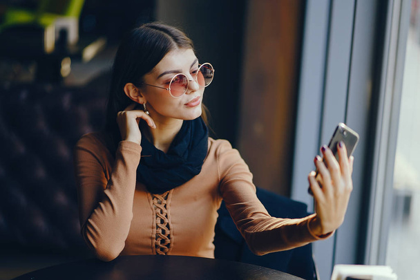 brunette girl using phone while at a restaurant - Foto, Imagen