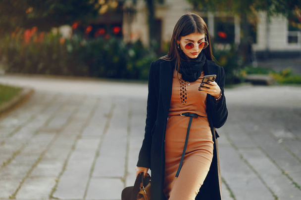 stylish girl walking through the city while using her phone - Foto, immagini