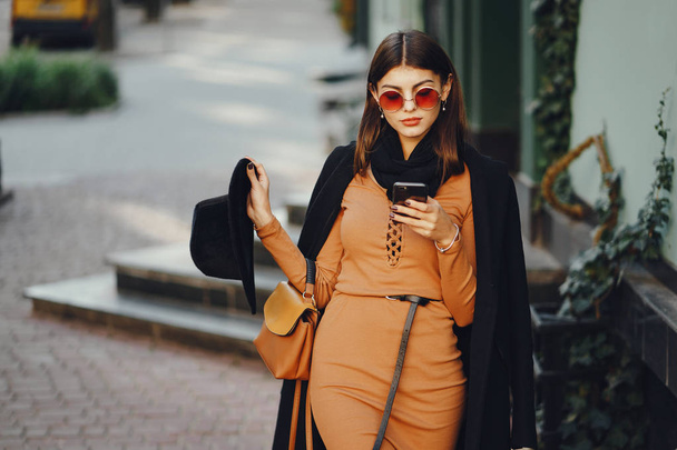stylish girl walking through the city while using her phone - Foto, Bild
