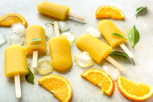 Orange popsicles with frozen juice and ice cubes, summer refreshing snack - Photo, Image