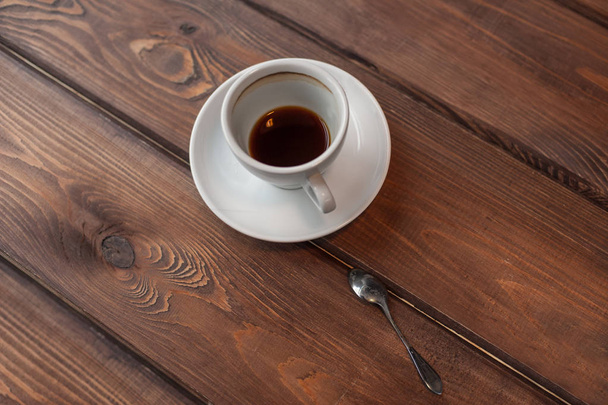 Half afgewerkte espresso in witte cup op houten tafel - Foto, afbeelding