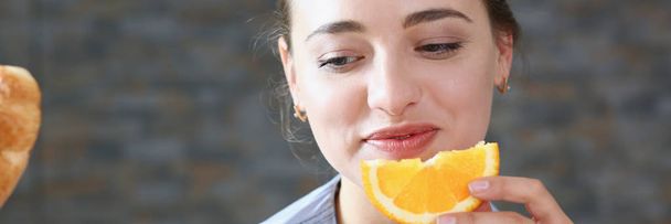 Красивая брюнетка улыбающаяся женщина ест нарезанный апельсин
 - Фото, изображение
