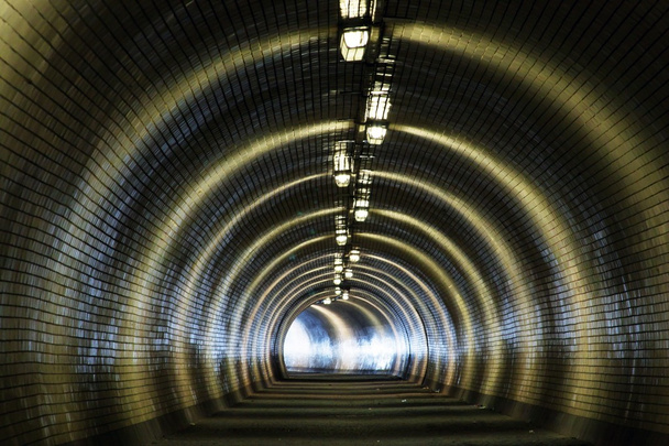 Vue à travers un tunnel sombre avec la lumière au bout
 - Photo, image