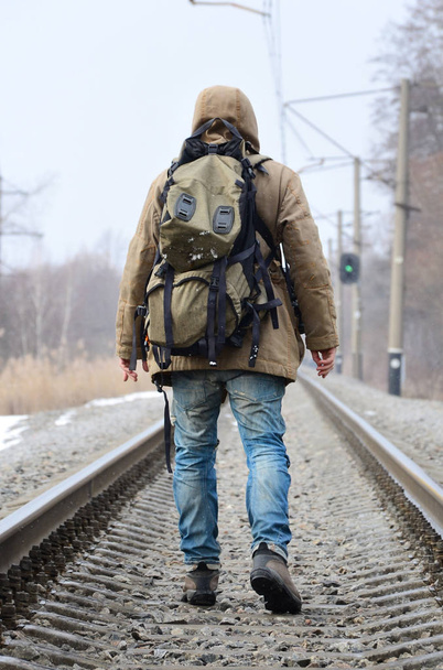 Bir adam büyük bir sırt çantası ile önde kış sezonu boyunca tren yolda gidiyor. - Fotoğraf, Görsel