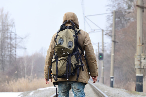 Bir adam büyük bir sırt çantası ile önde kış sezonu boyunca tren yolda gidiyor. - Fotoğraf, Görsel