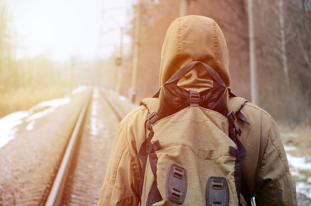 Un homme avec un grand sac à dos va de l'avant sur la voie ferrée pendant la saison d'hiver
 - Photo, image