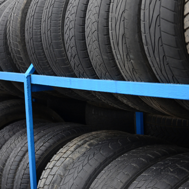 Rack with variety of car tires in automobile store. Many black tires. Tire stack background. Selective focus - Photo, Image