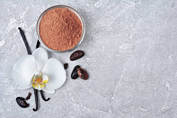 Vanilla pods with a flower, cacao powder and beans as ingredient for baking on gray concrete background - Foto, imagen