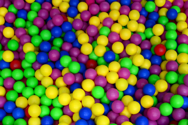 Muitas bolas plásticas coloridas em uma vala infantil em um playground. Padrão de close up
 - Foto, Imagem