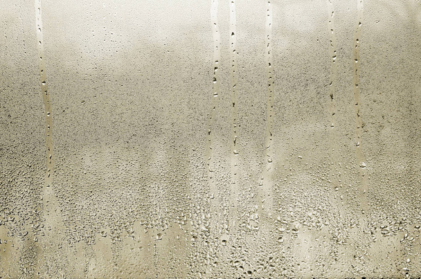 Texture of a drop of rain on a glass wet transparent background. Toned in yellow color - Photo, Image