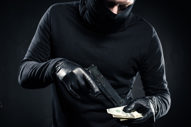 Hombre de pasamontañas negro con pistola y dólares
 - Foto, Imagen