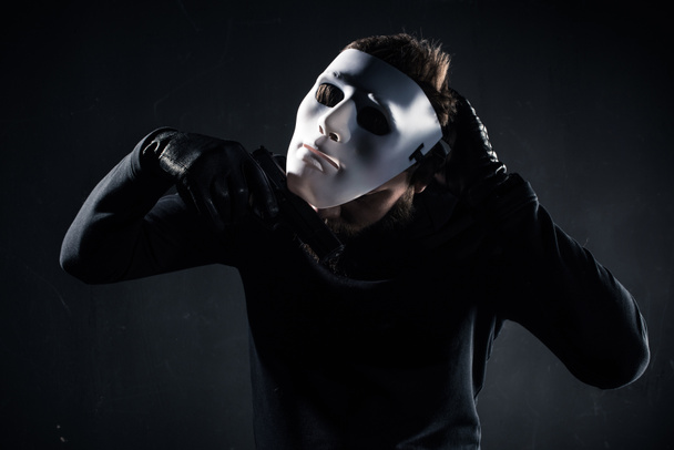 männlicher Krimineller nimmt weiße Maske vom Gesicht - Foto, Bild
