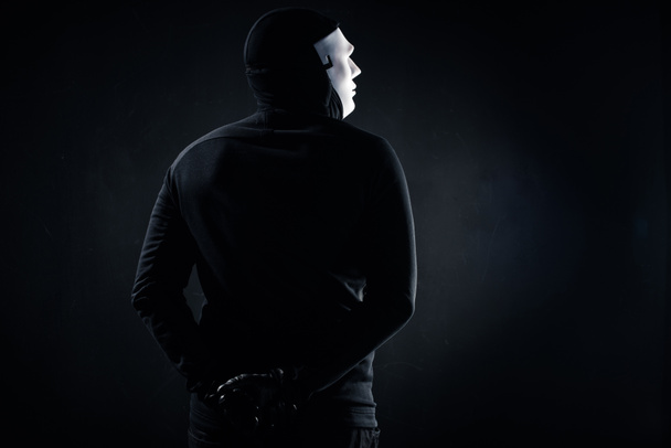 Вид сзади на преступника в маске и балаклаве
 - Фото, изображение