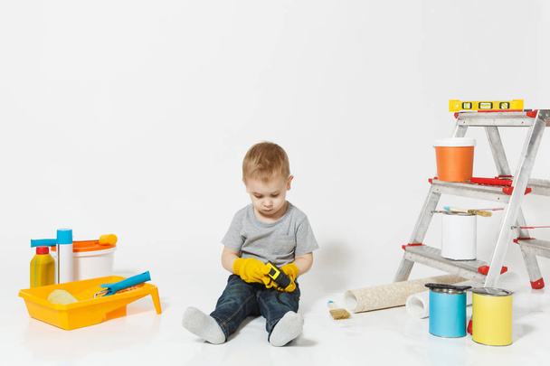 Aranyos kisfiú eszközök felújítás apartman szoba elszigetelt fehér háttér sárga kesztyű. Háttérkép, tartozékok ragasztás, festés eszközök. Home javítás. Szülői, gyermekkor fogalma. - Fotó, kép