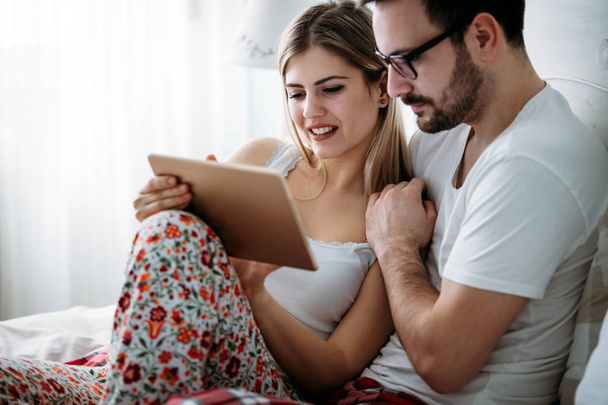 Young happy couple using digital tablet in bedroom - Foto, Imagem
