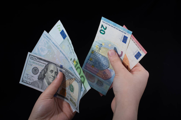 Hand-holding Amerikaanse dollar bankbiljetten geïsoleerd op zwarte achtergrond - Foto, afbeelding