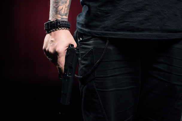 Close-up view of gun in male hand on red background - Photo, Image