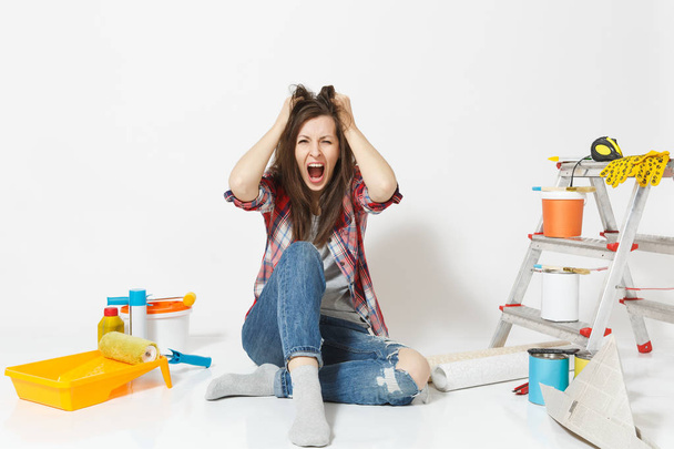 Confused screaming mad shocked woman sitting on floor with instruments for renovation apartment isolated on white background. Wallpaper, accessories for gluing, painting tools. Concept of repair home. - Photo, Image