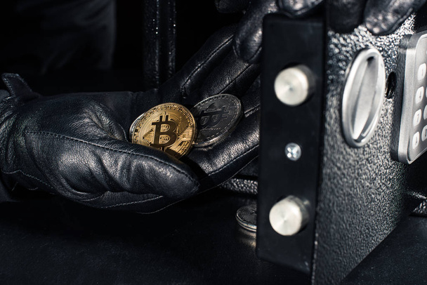 Thief hand stealing golden bitcoin from safe - Fotó, kép