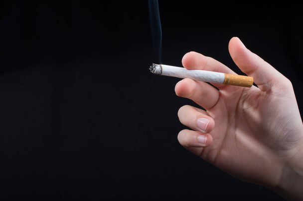 Hand is holding smoking cigarette with smoke around - Фото, зображення