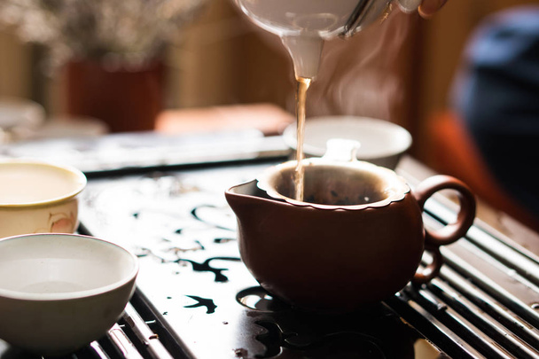 中国茶道でティーポットからプーアル茶を注ぐ。お茶を飲みながらの機器を設定します。 - 写真・画像