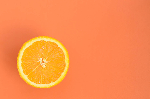 オレンジ色で明るい背景上のオレンジ色の果物のスライスを 1 つの平面図です。飽和の柑橘系テクスチャ画像 - 写真・画像
