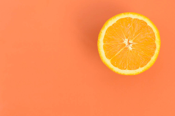 Top view of a one orange fruit slice on bright background in orange color. A saturated citrus texture image - Foto, afbeelding