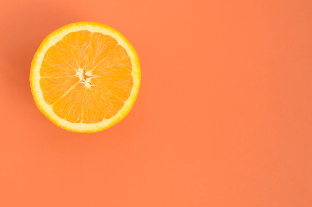 Top view of a one orange fruit slice on bright background in orange color. A saturated citrus texture image - Photo, Image