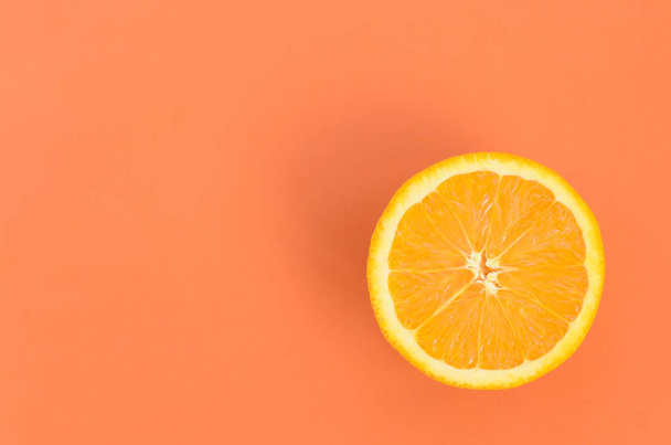 Top view of a one orange fruit slice on bright background in orange color. A saturated citrus texture image - Photo, Image