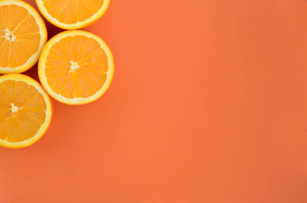Top view of a several orange fruit slices on bright background in orange color. A saturated citrus texture image - Fotografie, Obrázek