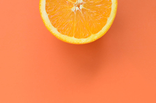 Top view of a one orange fruit slice on bright background in orange color. A saturated citrus texture image - Fotografie, Obrázek