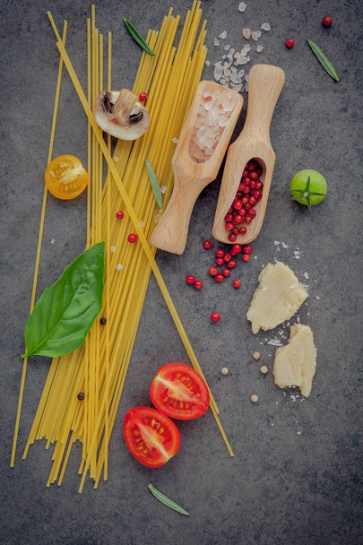 Concepto de comida italiana. Espaguetis con ingredientes de albahaca dulce, tomate, ajos de maíz, champiñón, calabacín y queso parmesano sobre fondo oscuro plano poner y copiar espacio
. - Foto, imagen