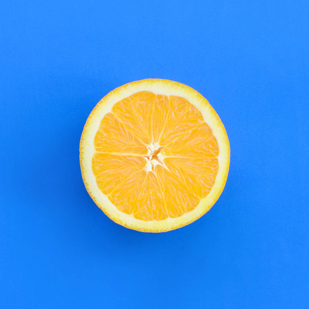 Top view of a one orange fruit slice on bright background in blue color. A saturated citrus texture image - Foto, Imagem
