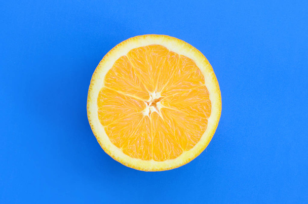 Vista superior de una rodaja de fruta naranja sobre fondo brillante en color azul. Una imagen de textura cítrica saturada
 - Foto, imagen