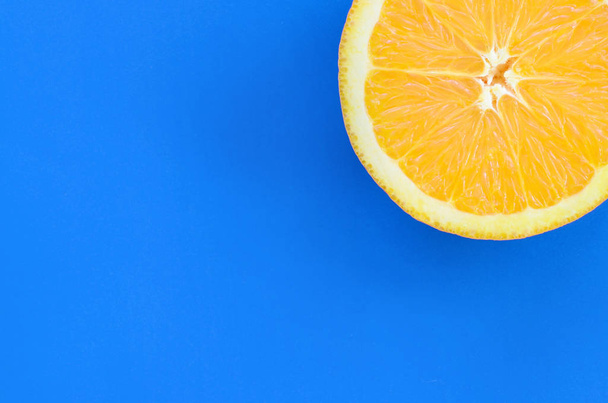 Вид зверху на один апельсиновий фруктовий шматочок на яскравому фоні синього кольору. Зображення насиченої цитрусової текстури
 - Фото, зображення